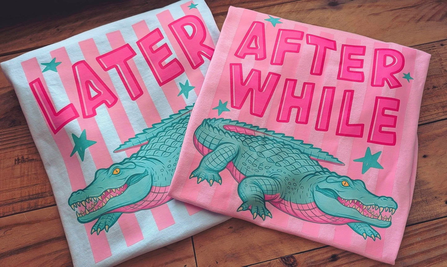 Two t-shirts with alligator graphics and text on a wooden surface