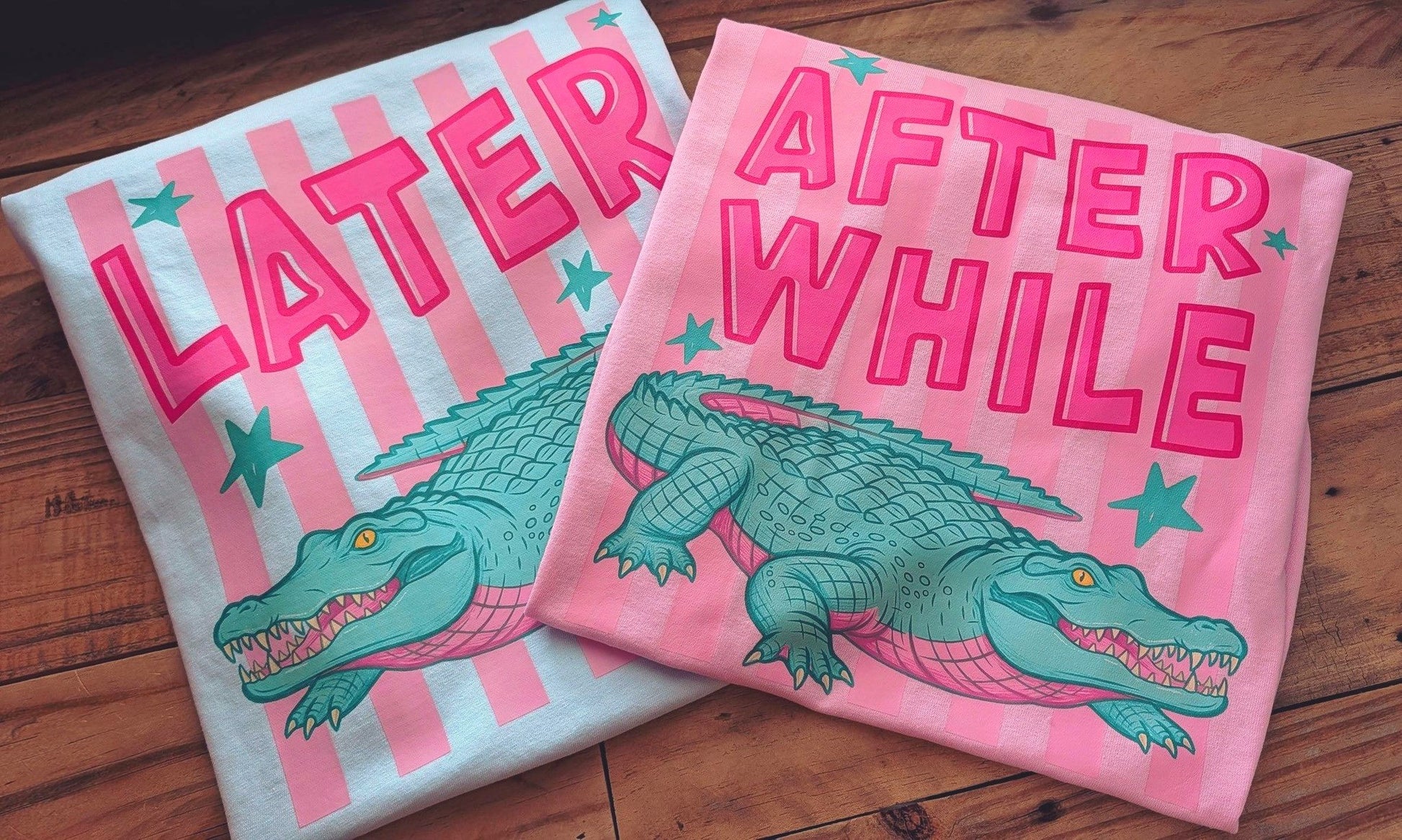 Two t-shirts with alligator graphics and text on a wooden surface