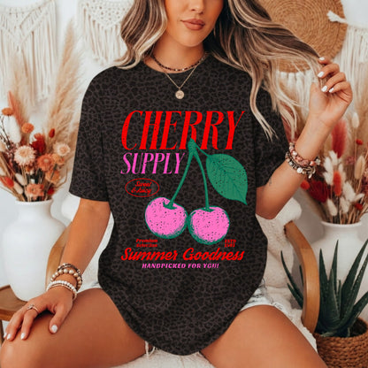 Person wearing a black t-shirt with 'Cherry Supply' graphic design in a decorative setting.