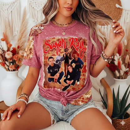 Person wearing a pink t-shirt with a graphic design, sitting in a decorative indoor setting.