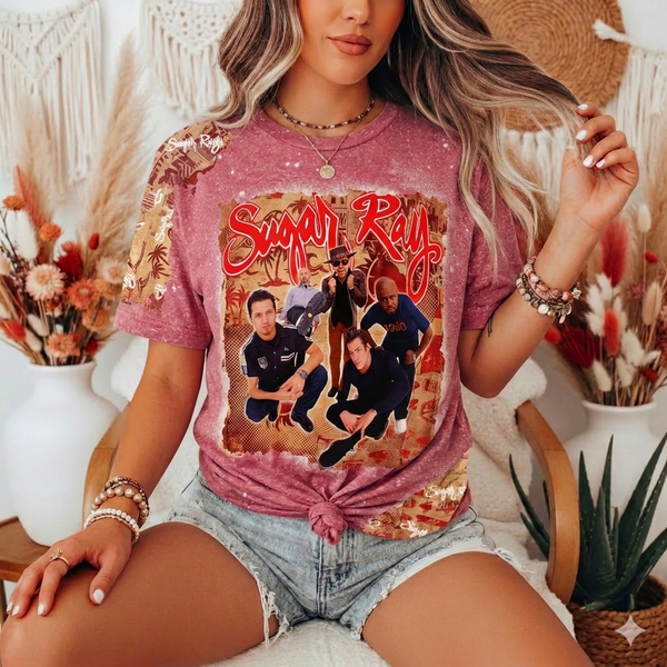 Person wearing a pink t-shirt with a graphic design, sitting in a decorative indoor setting.